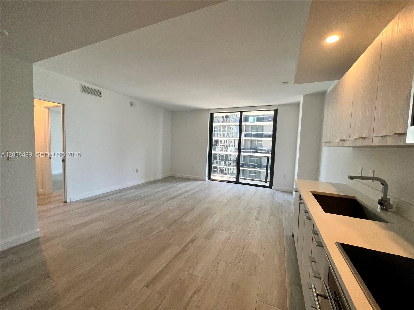 55 Southwest 9th Street, Unit 2702 Miami, FL 33130 - Photo 6 of 36 a view of an empty room with a window and wooden floor