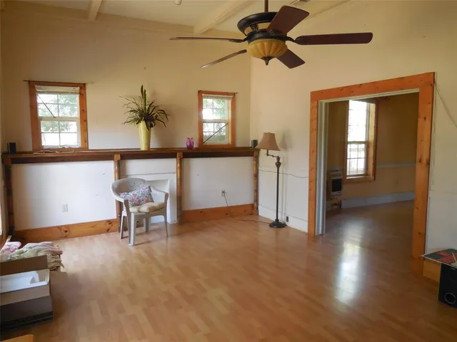 a view of an empty room with window and wooden floor