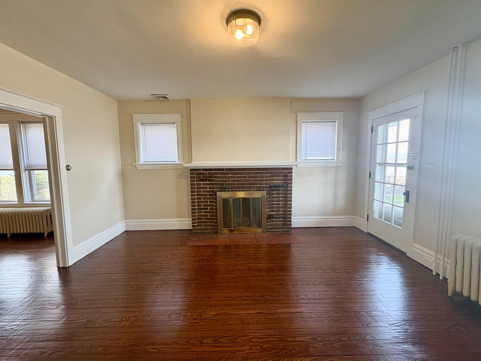 616 North Front Street Wormleysburg, PA 17043 - Photo 6 of 25 an empty room with wooden floor fireplace and windows