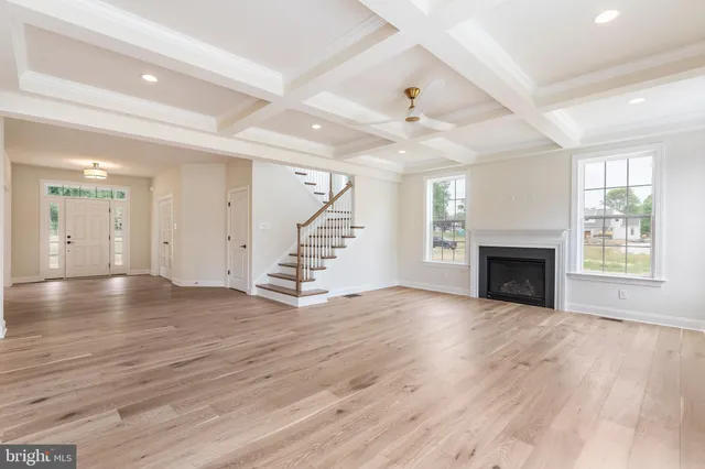 an empty room with wooden floor fireplace and windows