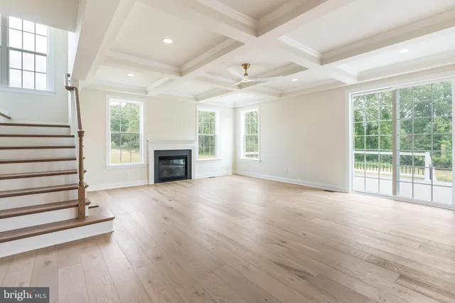 an empty room with wooden floor fireplace and windows
