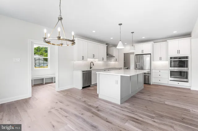 a large white kitchen with kitchen island a sink stainless steel appliances and cabinets