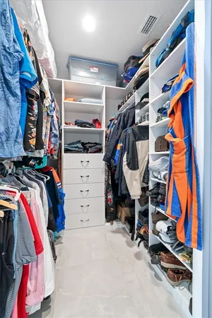 a view of walk in closet with clothes and shoes