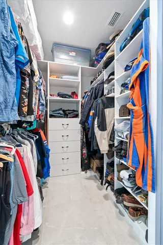 a view of walk in closet with clothes and shoes