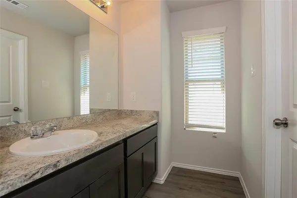 a bathroom with a granite countertop sink and a window