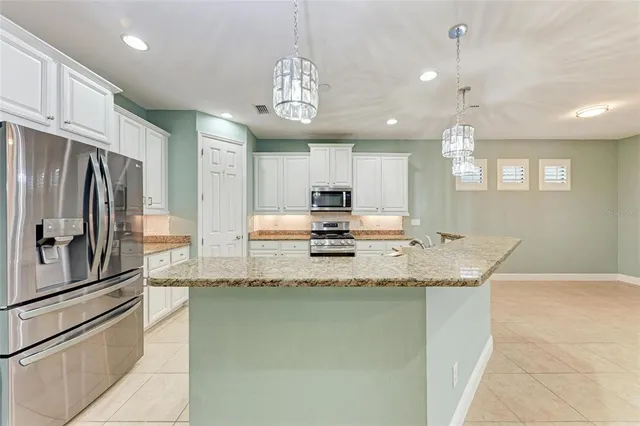 a large kitchen with granite countertop a large counter top a sink stainless steel appliances and cabinets