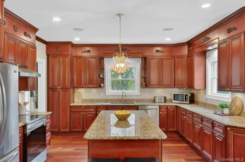 a open dining room with stainless steel appliances kitchen island granite countertop a table chairs and a wooden floor