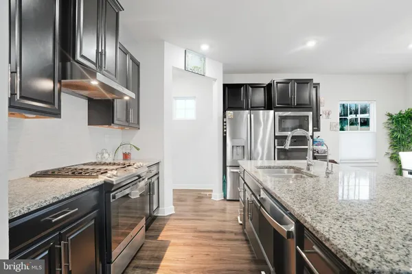 a kitchen with stainless steel appliances granite countertop a stove a sink and a refrigerator