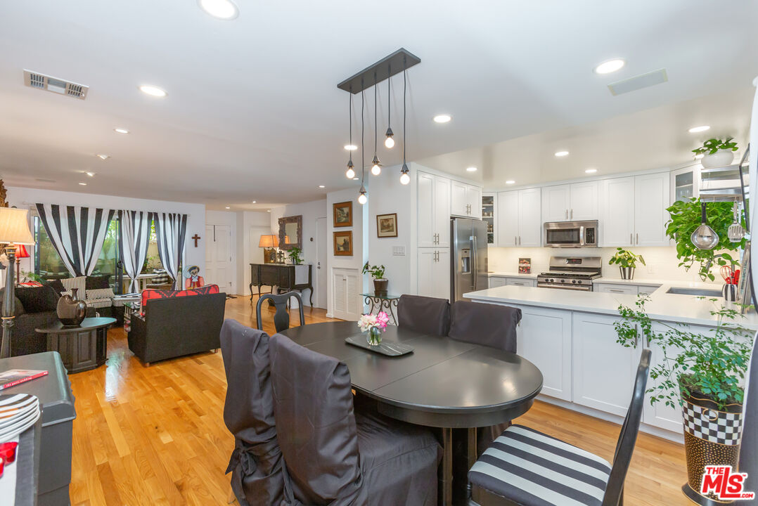 a kitchen with stainless steel appliances granite countertop a refrigerator dining table and chairs
