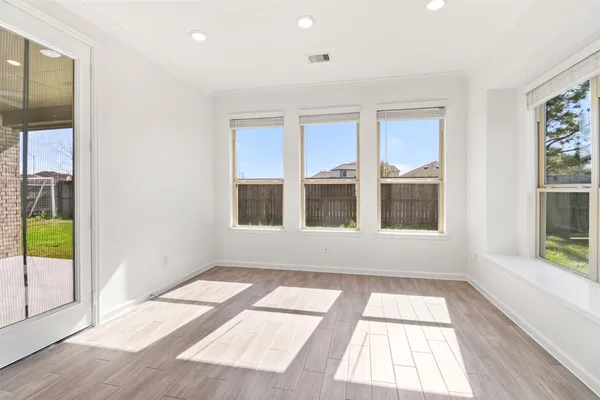 an empty room with wooden floor and windows