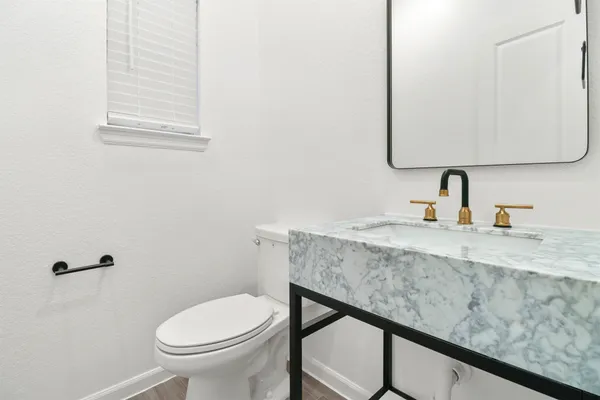 a bathroom with a granite countertop sink and a toilet