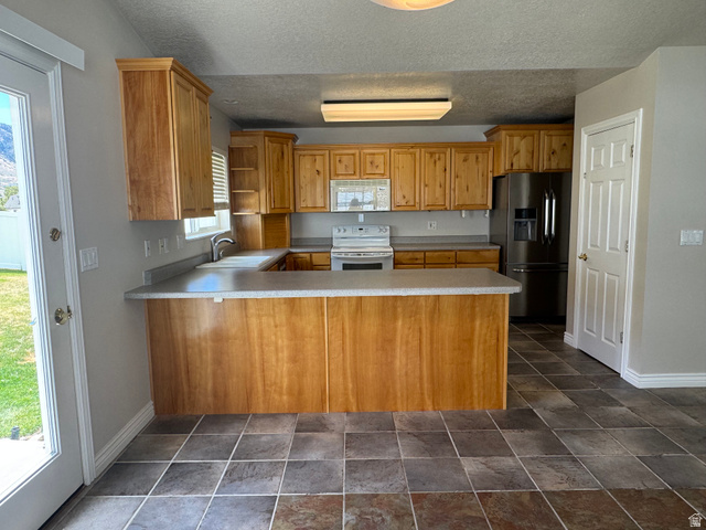 88 Canterbury Lane Logan, UT 84321 - Photo 14 of 37 U-shaped kitchen featuring wood cabinetry, laminate countertops, and a breakfast bar