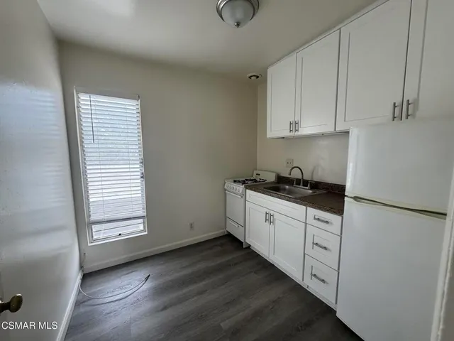 a kitchen with granite countertop white cabinets and white appliances