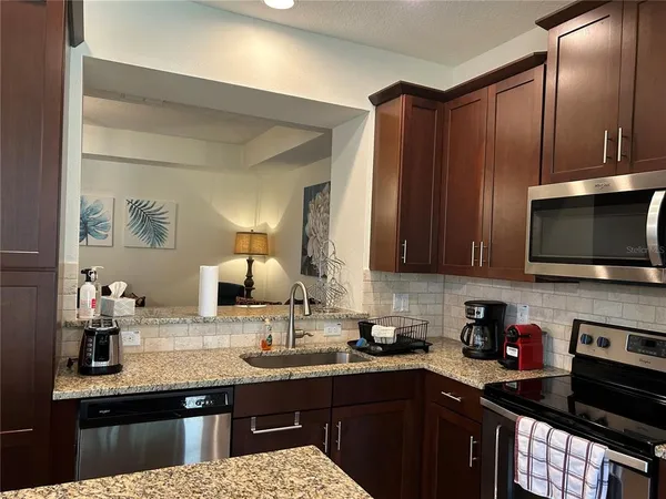 a kitchen with granite countertop a sink dishwasher stove and cabinets with wooden floor