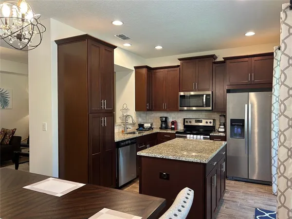 a kitchen with granite countertop stainless steel appliances a refrigerator cabinets and wooden floor