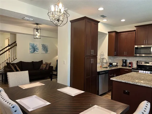 a living room with stainless steel appliances granite countertop furniture and a refrigerator