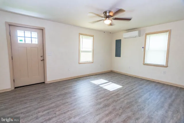 a view of an empty room with a window and wooden floor