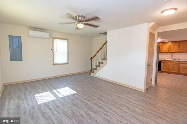 an empty room with wooden floor chandelier and windows