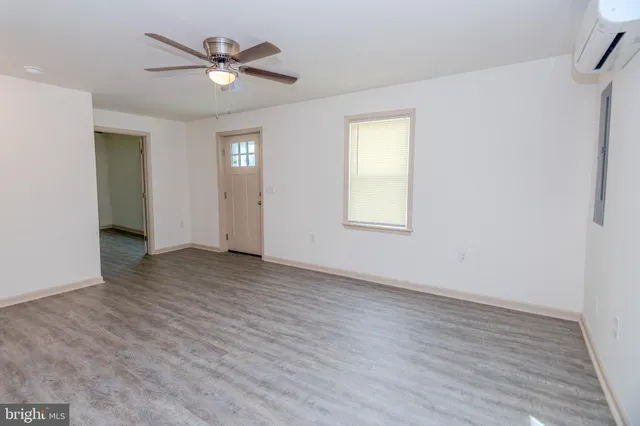 an empty room with wooden floor ceiling fan and windows