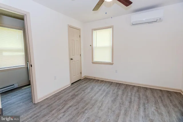 an empty room with wooden floor cabinet and windows