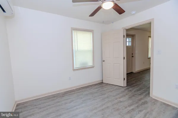 an empty room with wooden floor chandelier fan and windows