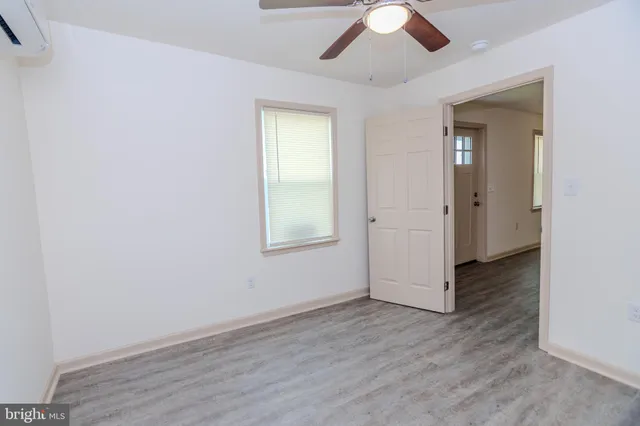 an empty room with wooden floor chandelier fan and windows