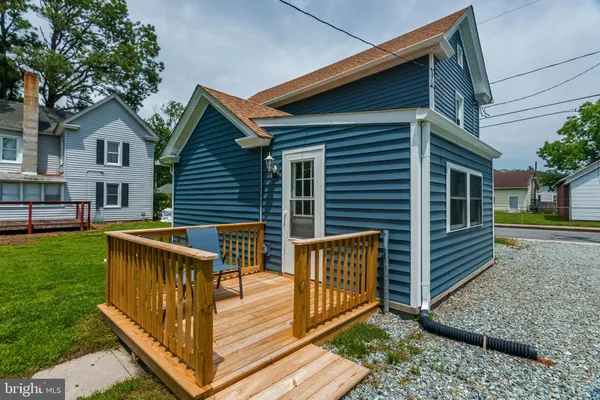 a view of house with a deck and a yard