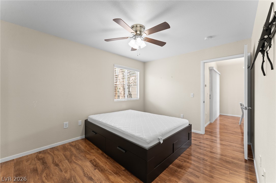 7950 West Flamingo Road, Unit 2142 Las Vegas, NV 89147 - Photo 20 of 24 A well-lit bedroom features warm wood flooring, offering a comfortable and inviting atmosphere.