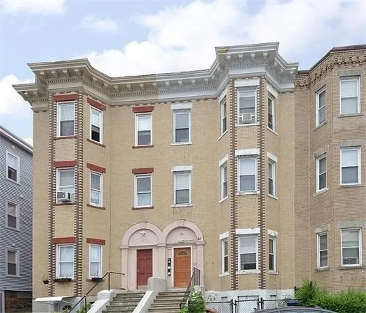 a front view of a brick building next to a yard