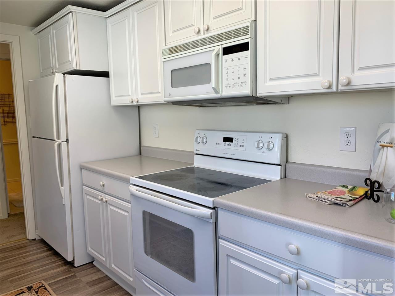 1216 Laredo Court Reno, NV 89503 - Photo 10 of 28 a kitchen with stainless steel appliances granite countertop white cabinets and a stove a refrigerator with wooden floor