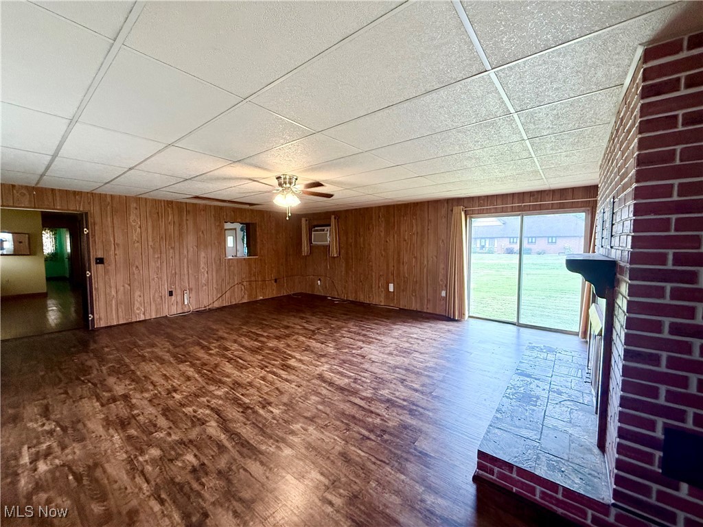 923 Archer Hill Road Colliers, WV 26035 - Photo 7 of 33 Unfurnished living room with wooden walls, ceiling fan, a paneled ceiling, and dark wood-style floors
