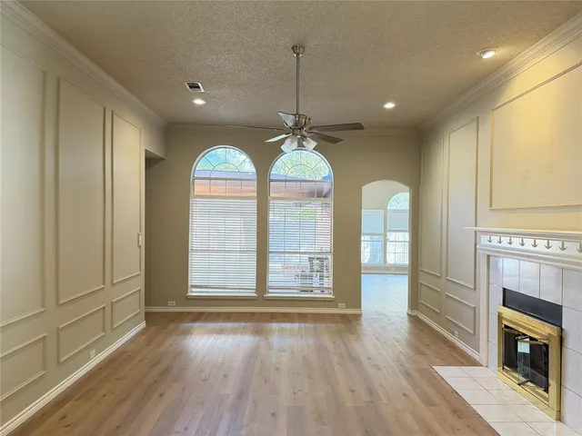 an empty room with wooden floor fireplace and windows