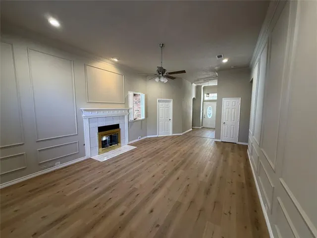 an empty room with wooden floor fireplace and windows