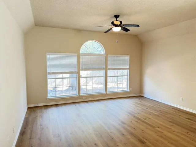 a view of an empty room with a window and wooden floor