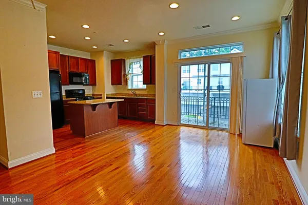 a open kitchen with stainless steel appliances granite countertop a stove top oven a sink with wooden floors and cabinets