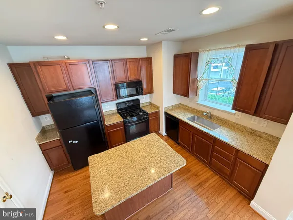a kitchen with stainless steel appliances granite countertop wooden cabinets a stove top oven a sink and dishwasher