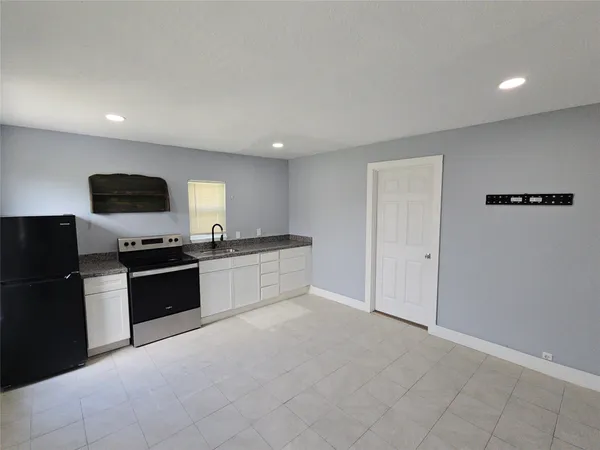 a large white kitchen with stainless steel appliances a large counter top and a stove top oven