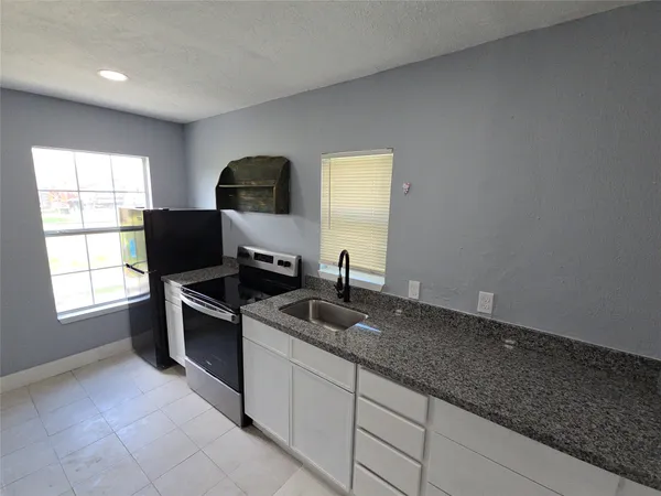a kitchen with granite countertop a sink stove and cabinets