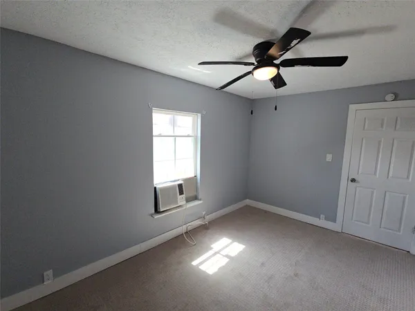 an empty room with windows and fan