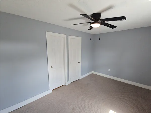 an empty room with a ceiling fan and a fan