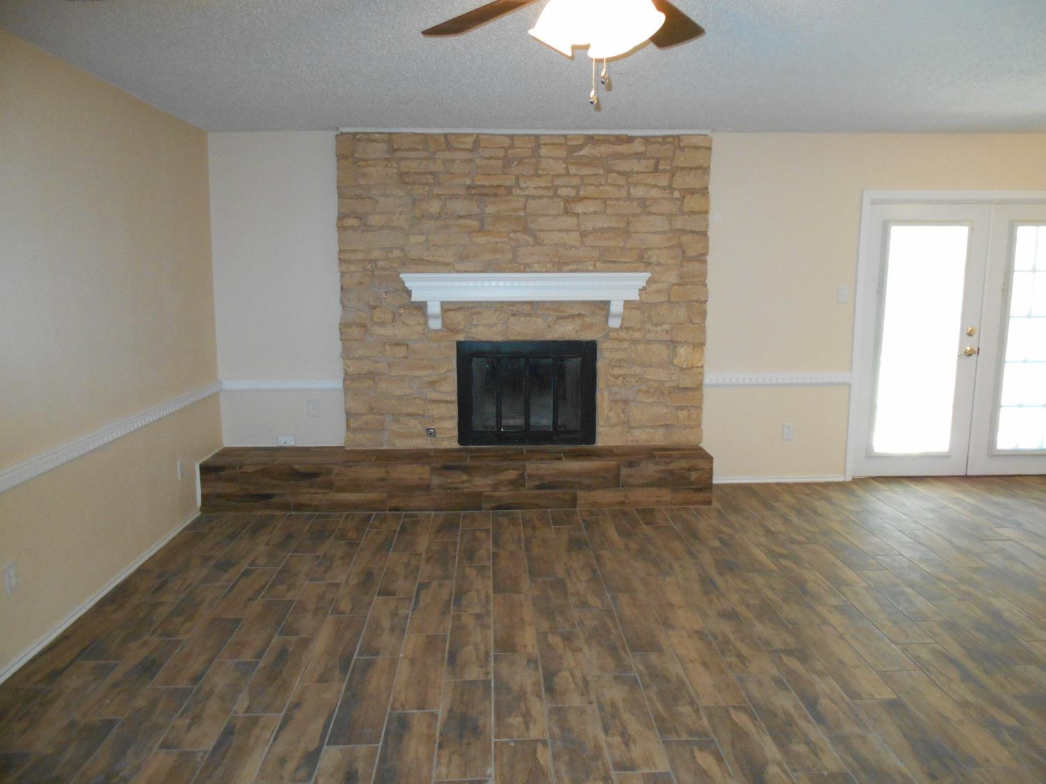 5739 Emory Street Lubbock, TX 79416 - Photo 5 of 14 an empty room with wooden floor and chandelier