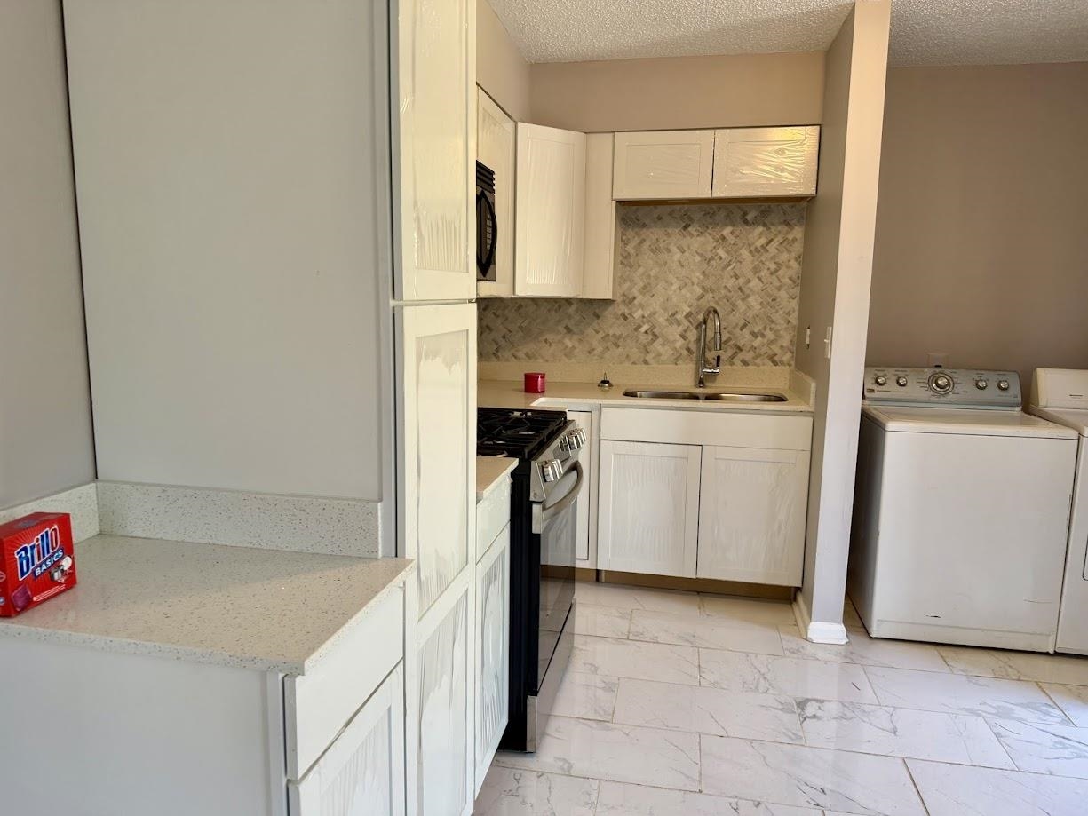 2215 Henrietta Road Memphis, TN 38134 - Photo 3 of 10 Kitchen with black gas stove, white cabinets, light marble finish floors, a textured ceiling, and washing machine and clothes dryer