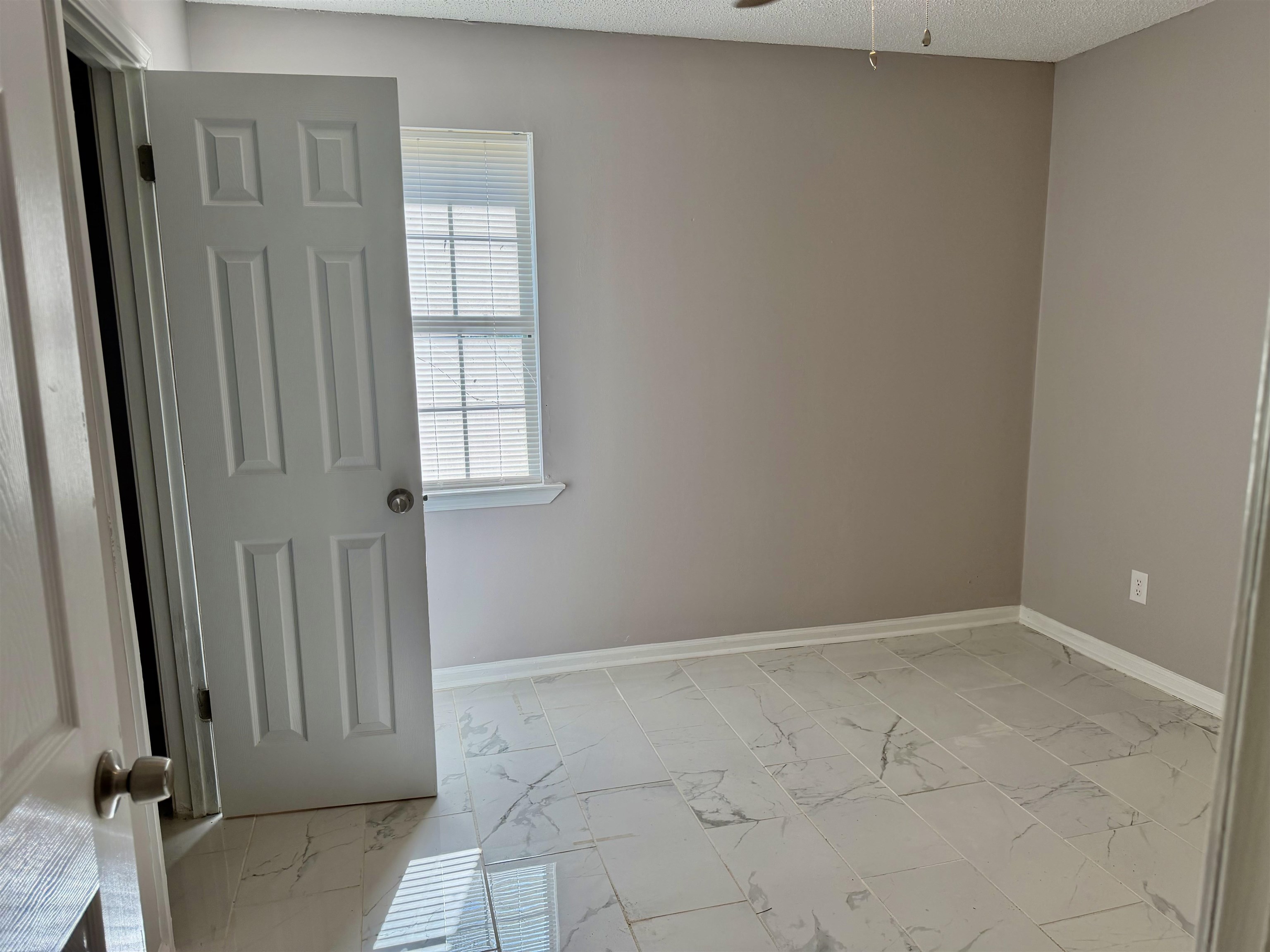 2215 Henrietta Road Memphis, TN 38134 - Photo 7 of 10 Unfurnished room featuring light marble finish flooring, ceiling fan, and a textured ceiling