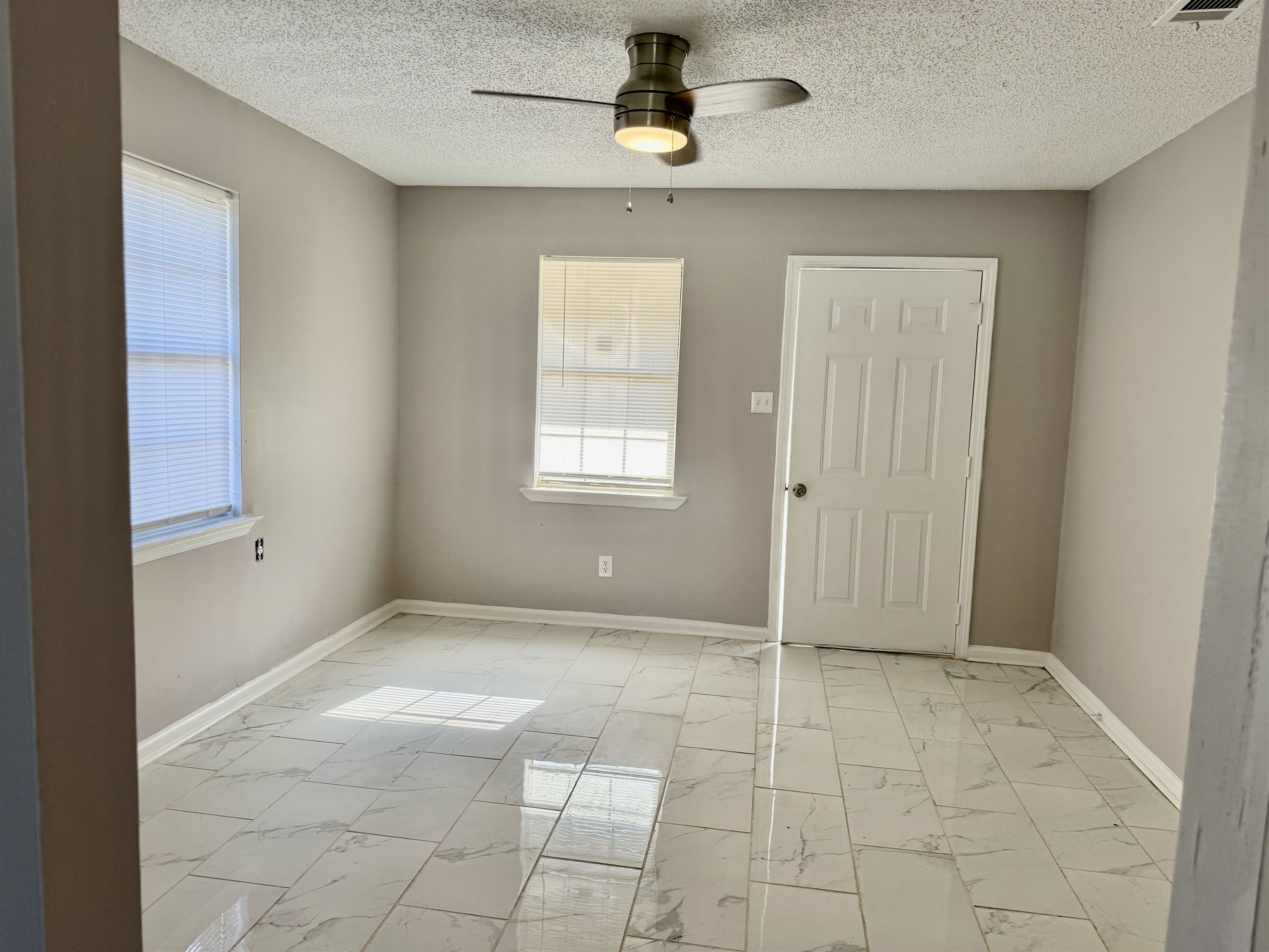 2215 Henrietta Road Memphis, TN 38134 - Photo 9 of 10 Empty room with light marble finish floors, a ceiling fan, plenty of natural light, and a textured ceiling