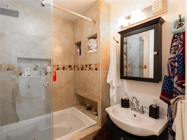 a bathroom with a sink and mirror with bathtub
