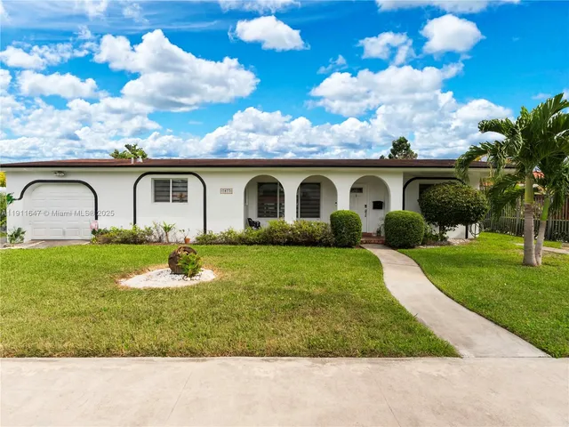 a front view of house with garden and trees