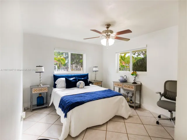 a bedroom with a bed a chair and potted plant on the dresser