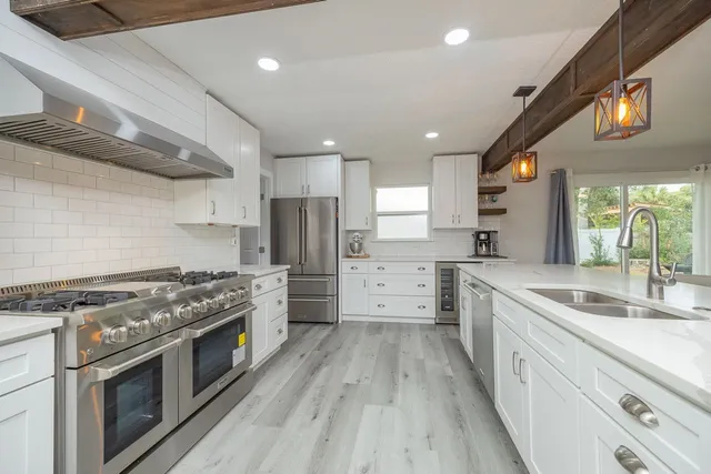 a kitchen with stainless steel appliances a refrigerator cabinets and wooden floor