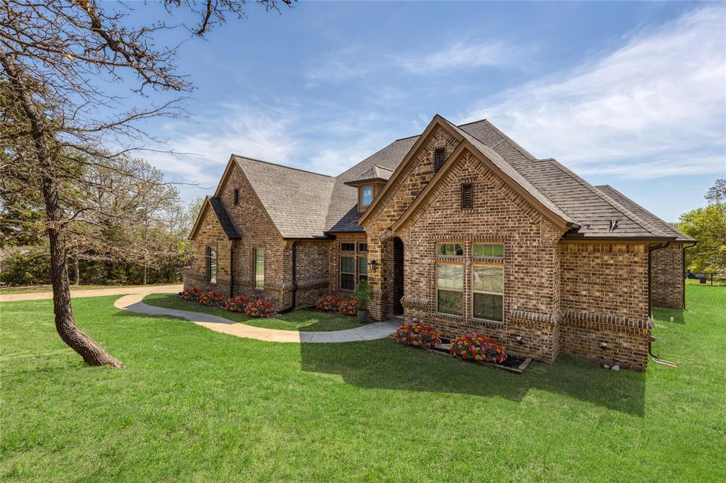 143 Wrigley Drive Springtown, TX 76082 - Photo 10 of 40 Virtually Staged - Brick exterior with gabled rooflines, a concrete walkway, and a manicured lawn