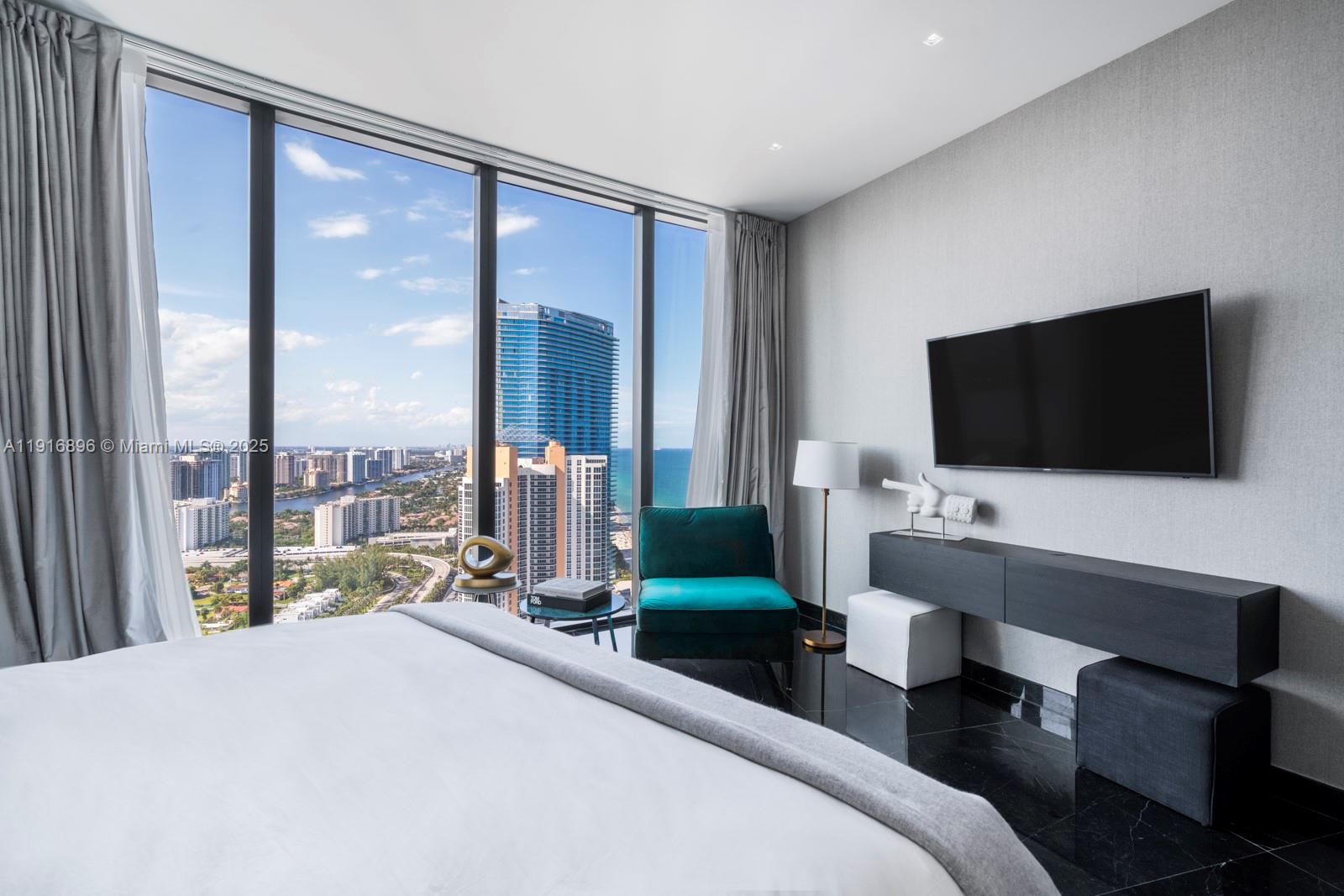 18555 Collins Avenue, Unit 3505 Sunny Isles Beach, FL 33160 - Photo 15 of 52 a bedroom with a bed and a flat screen tv